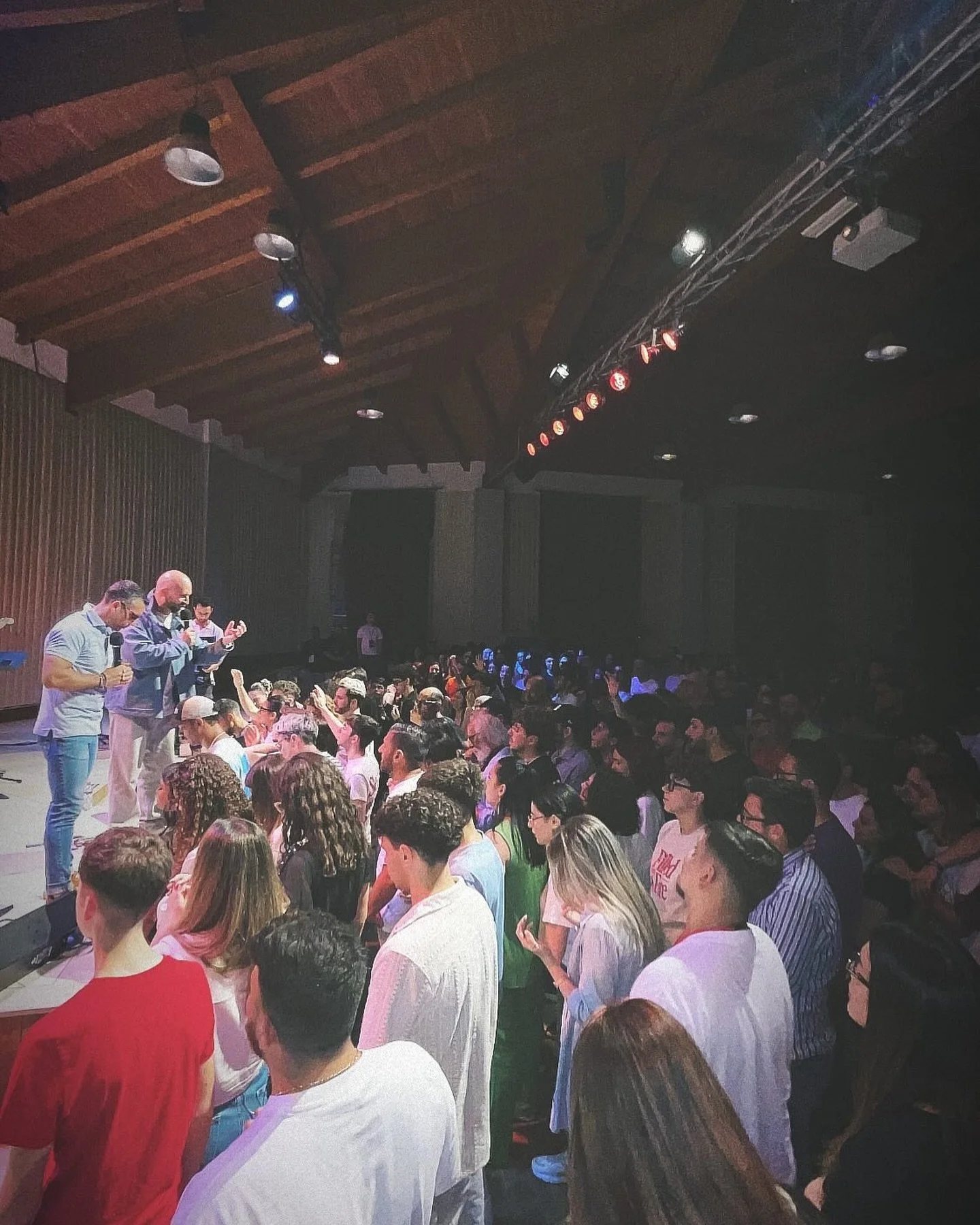A crowd worshiping with hands raised