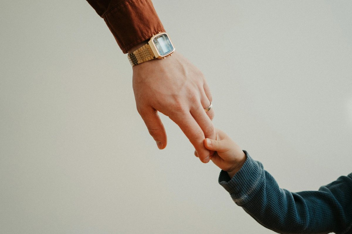 A parent's hand holding a child's hand